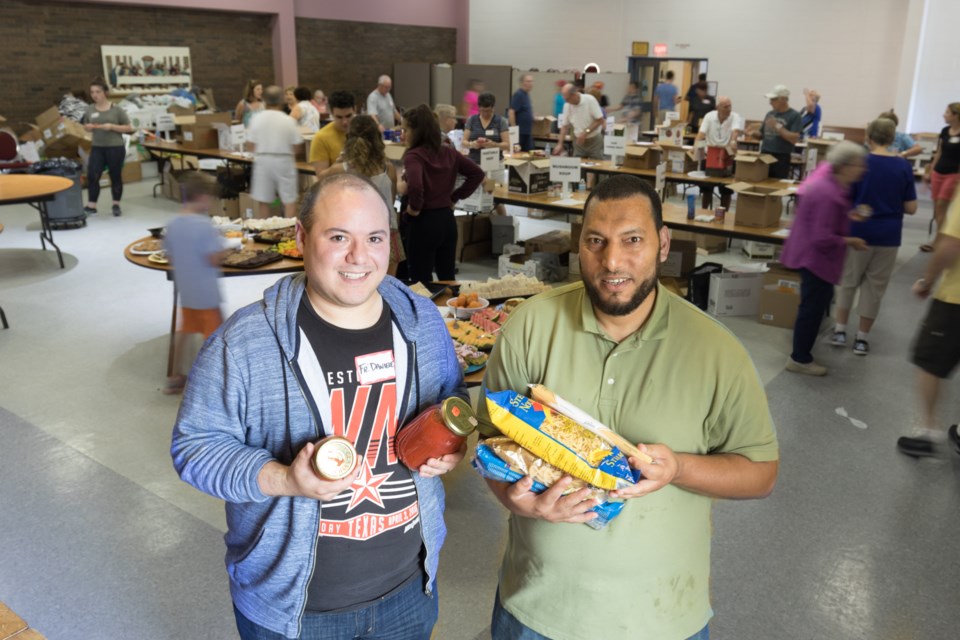 (From left) Roman Catholic Father Daniele Musclino and Muslim Imam Saber Alkalani worked together like pasta and sauce at St. Jerome Roman Catholic Church during the St. Vincent Place Big Blue Box Drive on Saturday. Jeff Klassen/SooToday