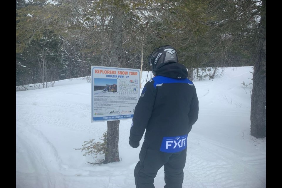 This snowmobile tour is one of the only in the province that has an extensive number of educational stops.  In this case, it is the author reading the sign, Back Roads Bill. 