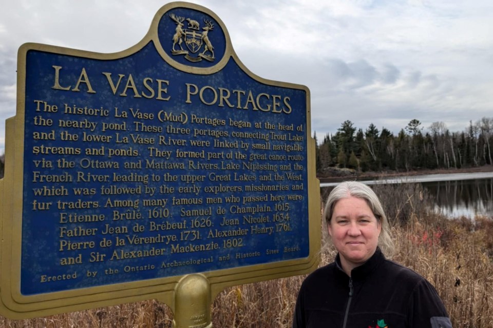 Laura Kielpinski stands beside the La Vase Portages historic plaque on Hwy. 17 just east of North Bay at Dugas Bay. There were several ways to cross the height of land to Lake Nipissing in pre-colonial times.