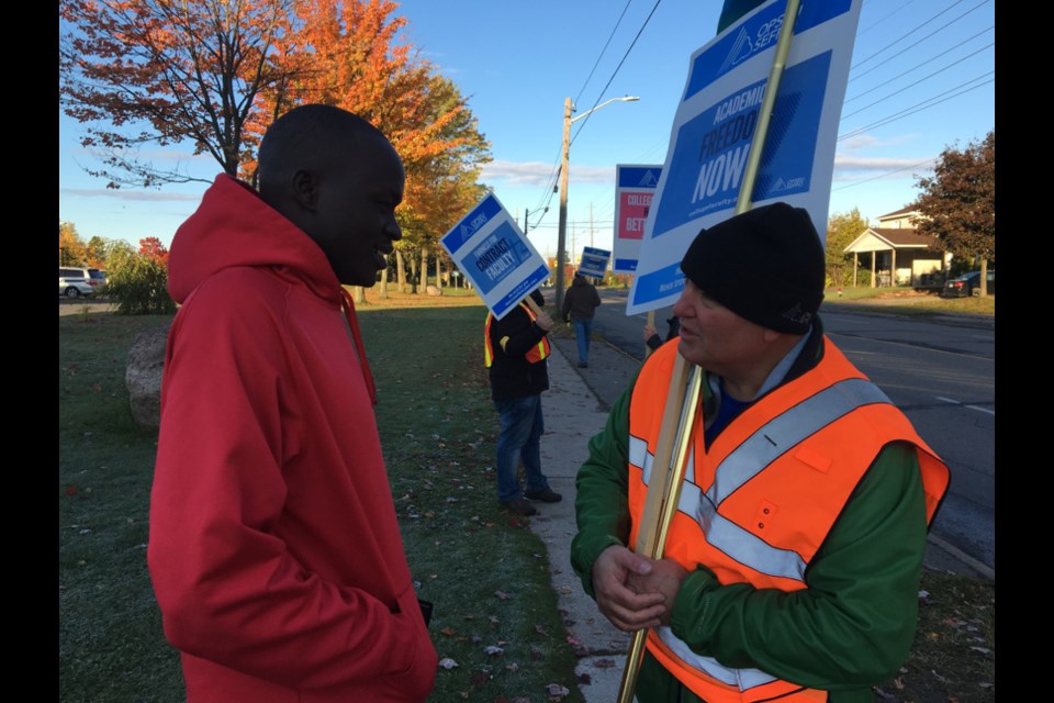 Frank Turco of OPSEU Local 613 speaks to Sault College student Rik Lam on the picket line, Oct. 16, 2017. Darren Taylor/SooToday
