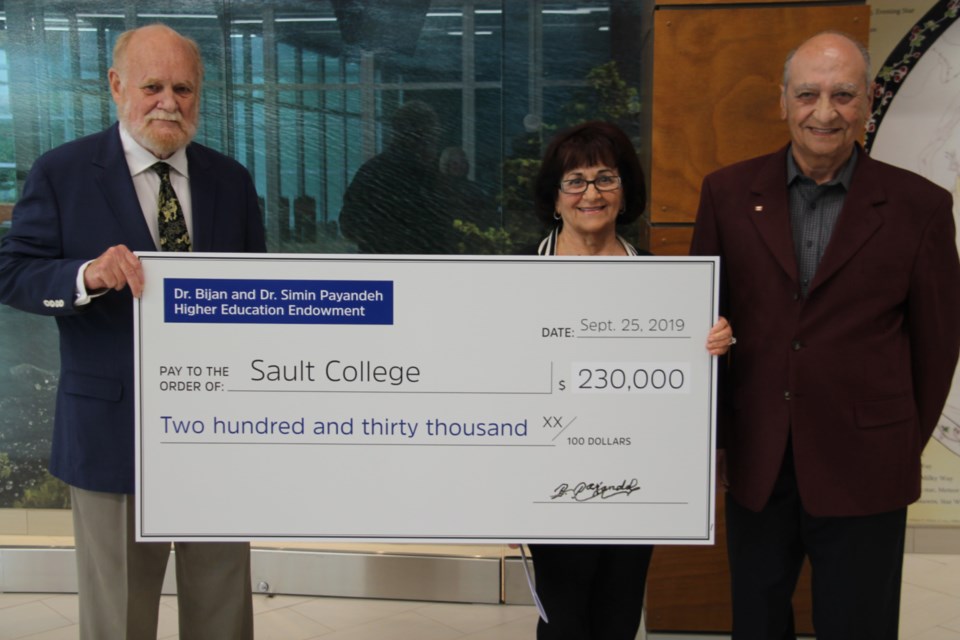 Ron Common, Sault College president, receives a scholarship cheque for $230,000 on behalf of the college from Dr. Simin Payandeh and Dr. Bijan Payandeh, Sept. 25, 2019. Darren Taylor/SooToday