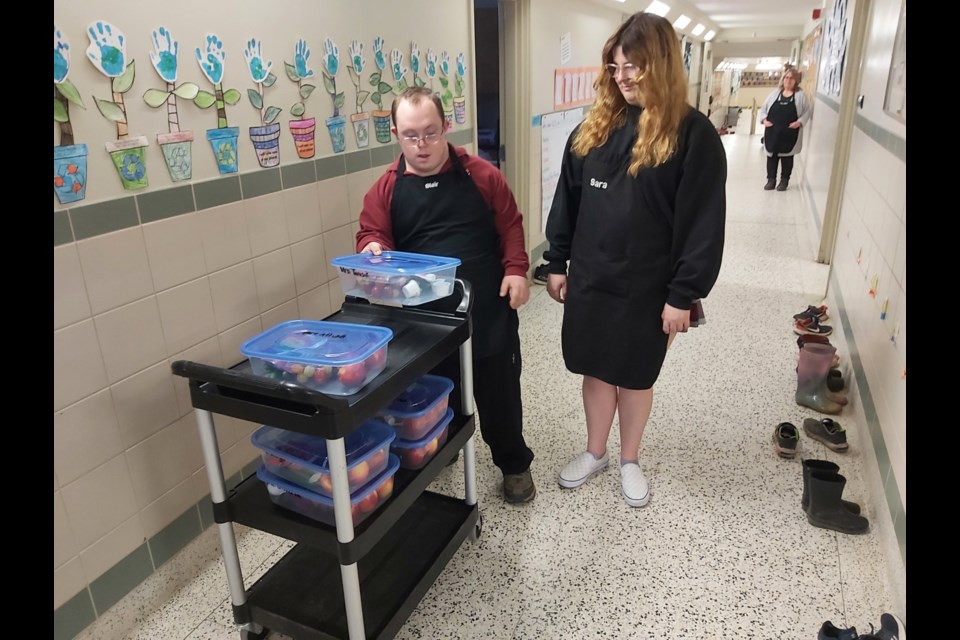 Blair Driscoll and Sara Sangestino, students in the St. Mary’s College Independent Living Skills program, taught by Patsy Reid, H-SCDSB ILS educational assistant, prepare and deliver breakfast program snacks three times a week at Our Lady of Lourdes school.