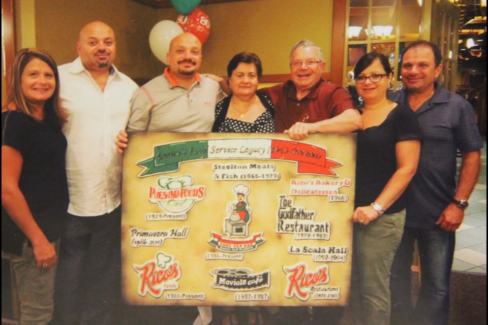 Enrico Ianni-Palarchio and family with a board showing the logos of all the businesses he started in Sault Ste. Marie. Photo provided