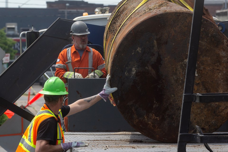 Workers position a ruptured oil tank on a flatbed after it was removed from the Canadian Pacific Kansas City rail yard.