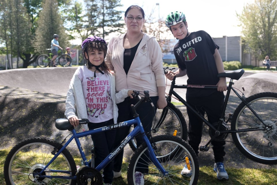 Chantel Combs (centre) and her two kids Elizabeth, 9, (left) and Andrew, 13, (right) at the Esposito Park pump track 'Summer Kickoff' event on Saturday. Elizabeth and Andrew received new bikes. Jeff Klassen/SooToday
