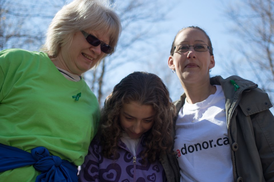 Savanna Zayet, 10, (centre) acts quite shy while posing for a photo. Zayet received a new heart after being diagnosed with histiocytoid cardiomyopathy when she as just two-years-old. Savanna, her mother Terri Zayet(right), and her grandmother Bev Carscadden (left) attended the Transplant Trot charity walk on Saturday. Jeff Klassen/SooToday