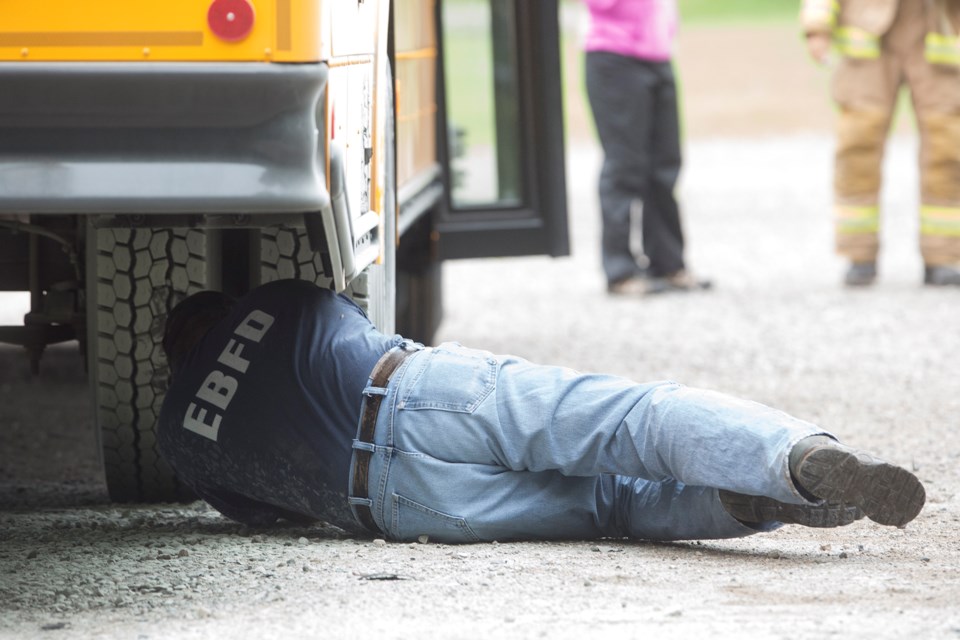 Damage to the underside near the gas tank is examined on a school bus that was involved in a small fire this afternoon at St. Kateri Outdoor Learning Centre. Kenneth Armstrong/SooToday