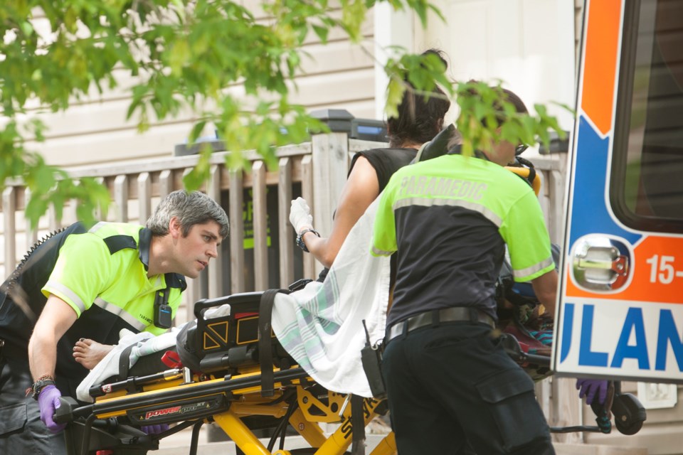 A woman treated for burns with bandages on her hands is placed into an ambulance by EMS staff after a fire today on People's Road. Kenneth Armstrong/SooToday