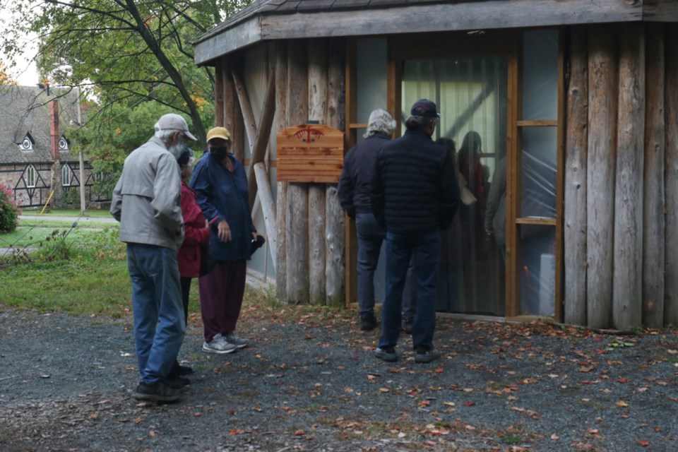 People enter the arbour beside the former site of Shingwauk Residential School to sit at the sacred fire Thursday morning. 