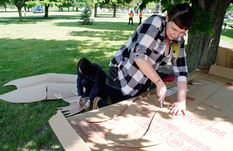 Community artists Peter Mozarowski (left) and Rihkee Strapp work on a three-person cardboard turtle puppet outside the Art Gallery of Algoma on Friday, June 26, 2015. The puppet is being made for Saturday's International Bridge Walk. Michael Purvis/SooToday