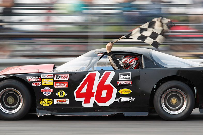Dan Byrnes carries the checkered flag following his Super Late Model heat race victory SooToday.com/Kenneth Armstrong