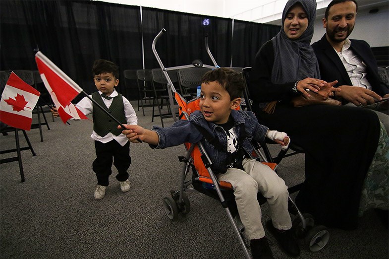 Children wave Canadian flags immediately prior to a citizenship ceremony as part of Passport to Unity on May 1, 2015 at Sault College. Kenneth Armstrong/SooToday