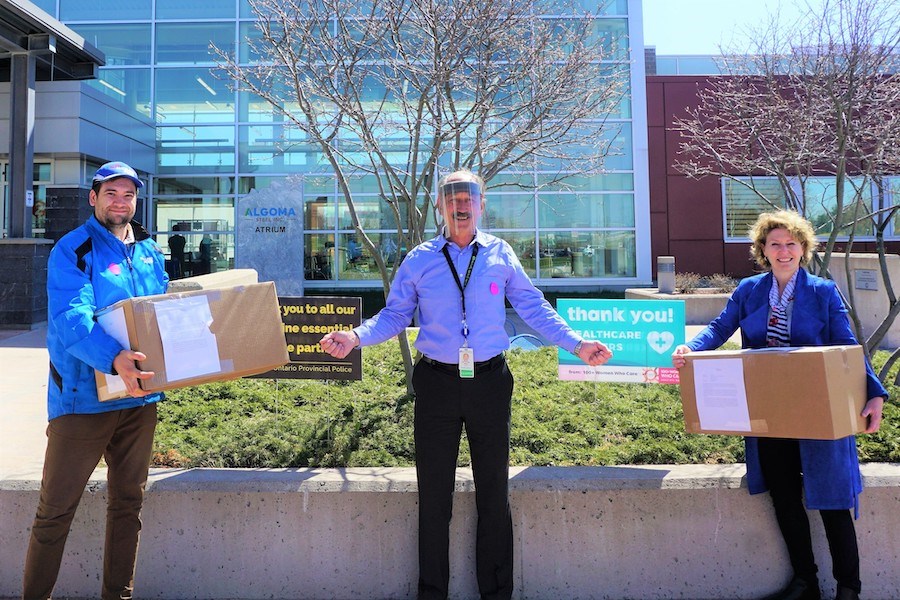 Mike Gualtierie (from Highland Ford) and Judith Kovala (Maitland Ford Lincoln) present face shields to Mike Polychuk (Logistics, SAH). Image supplied