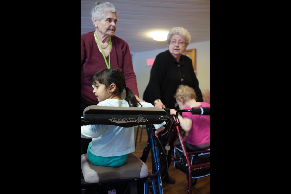 Ontario Finnish Nursing Home residents Nancy Volpe (left) and Marion McLeod (right), both 87, give walker rides to Gia (left) and Nancy (right) from Jessie Irving Daycare as part of a weekly intergenerational visitation program. Jeff Klassen for SooToday