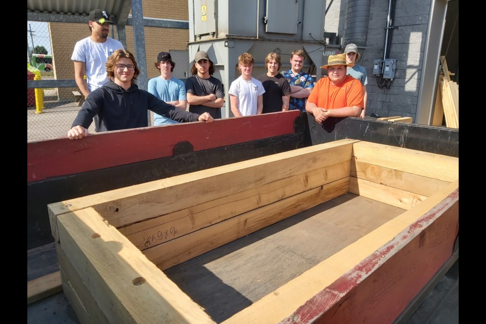 Superior Heights Collegiate Grade 11 technical shop students with one of three wooden raised planter beds they constructed for use by Ontario Finnish Resthome Association residents, June 2, 2023.