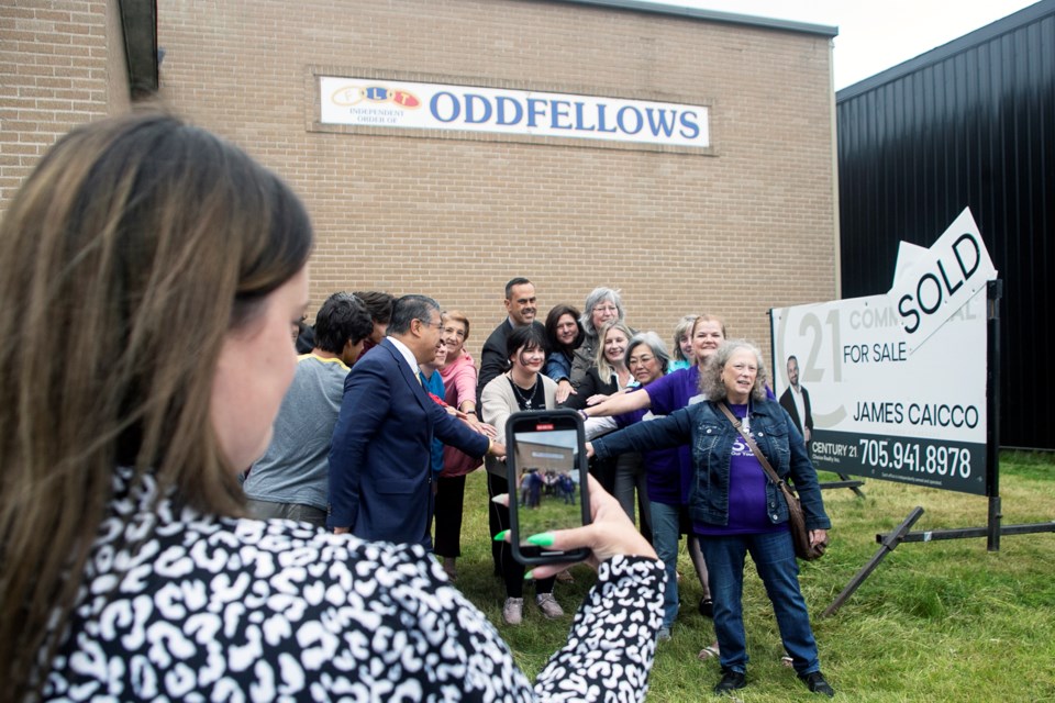 Community partners pose next to a sold sign for the former Odd Fellows Hall on Dennis Street that will be converted into a Youth Wellness Hub.