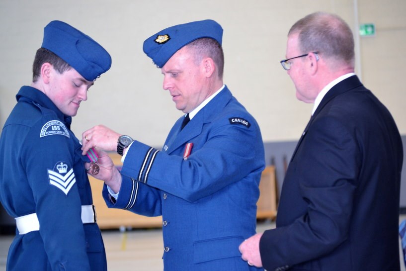 Provided photo shows: L-R Flight Sergeant Zack Nott receives the Lord Strathcona Medal of Merit from Captain James Browne accompanied by Mr. Martin Galvin. Photo Credit: Peter Grant