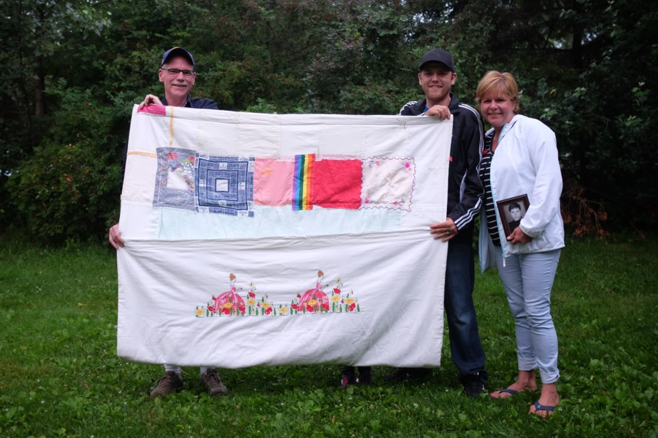 Stéphane Dosko lived with HIV for 17 years before passing away in 2007. (Left to Right) Dosko's husband Steve Miller, his nephew Justin Baxter, and his sister Tania Dosko hold 'The Quilt', a keepsake with a special message that Stéphane put together before he passed away. Photo by Jeff Klassen for SooToday
