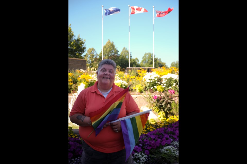 Sault Pride's Susan Rajamaki holding Pride flags in front of City Hall. Rajamaki said in 2013 City Hall refused to put up a Pride flag in support of LGBT rights and that led to the creation of the first Sault Pridefest in 2014. Photo by Jeff Klassen for SooToday