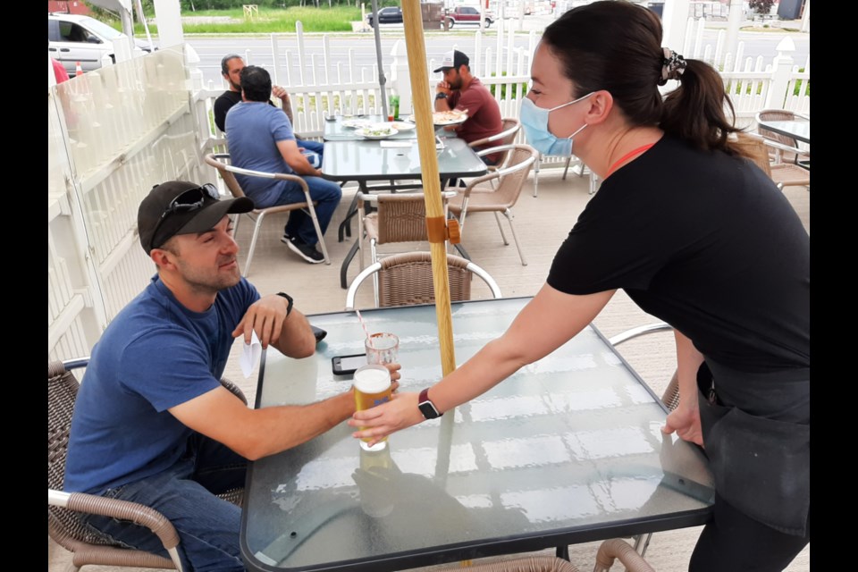 While still observing COVID-19 restrictions, Saultites are once again getting their hair styled, shopping at malls and enjoying food and beverages on patios. Here, Jenna Larue serves a beverage to Jonathan Major at Fratelli’s Kitchen & Pizzeria, June 20, 2020. Darren Taylor/SooToday