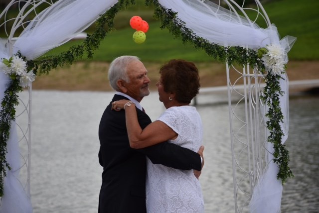 Chet Babcock and Lorrie Zorzit seen on their wedding day in Grand Rapids, Michigan, under an arch decorated with pickleballs.