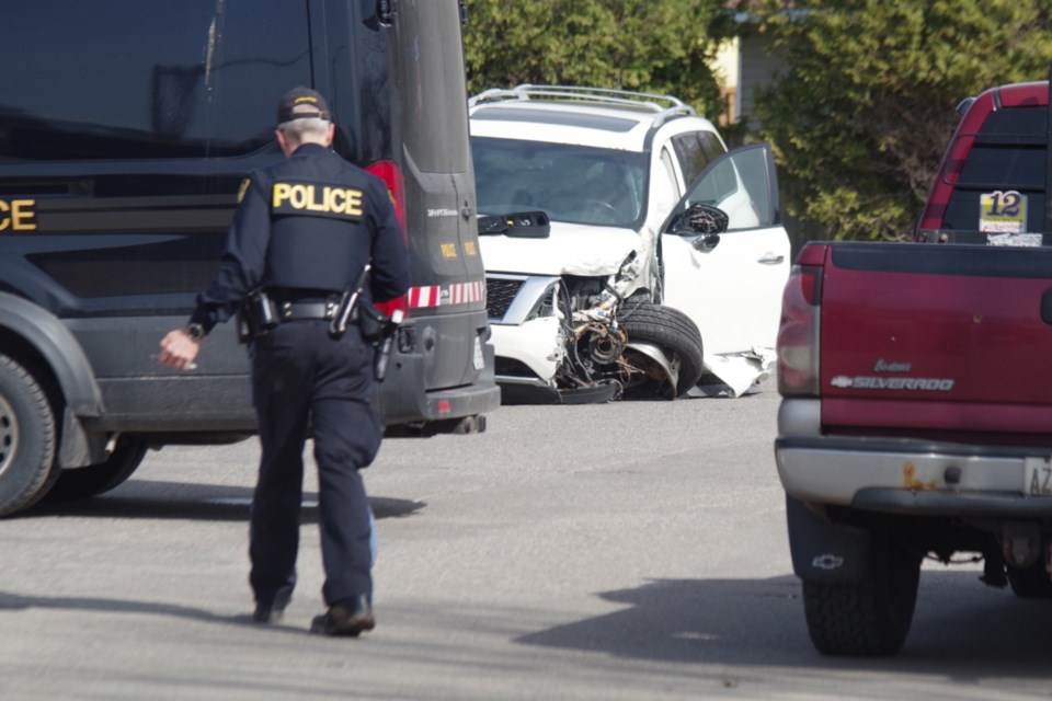 Police examine a severely-damaged SUV hours after a crash on Queen Street East.