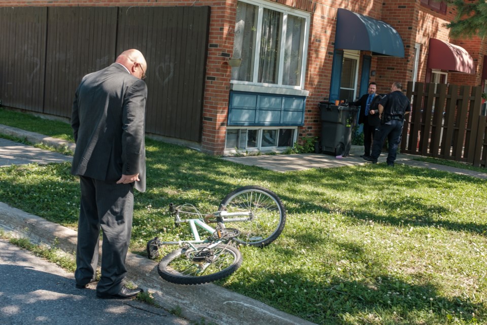 Sault Ste. Marie City Police Service investigator examines a bike outside a home on Boston Ave. July 16. Jeff Klassen/SooToday