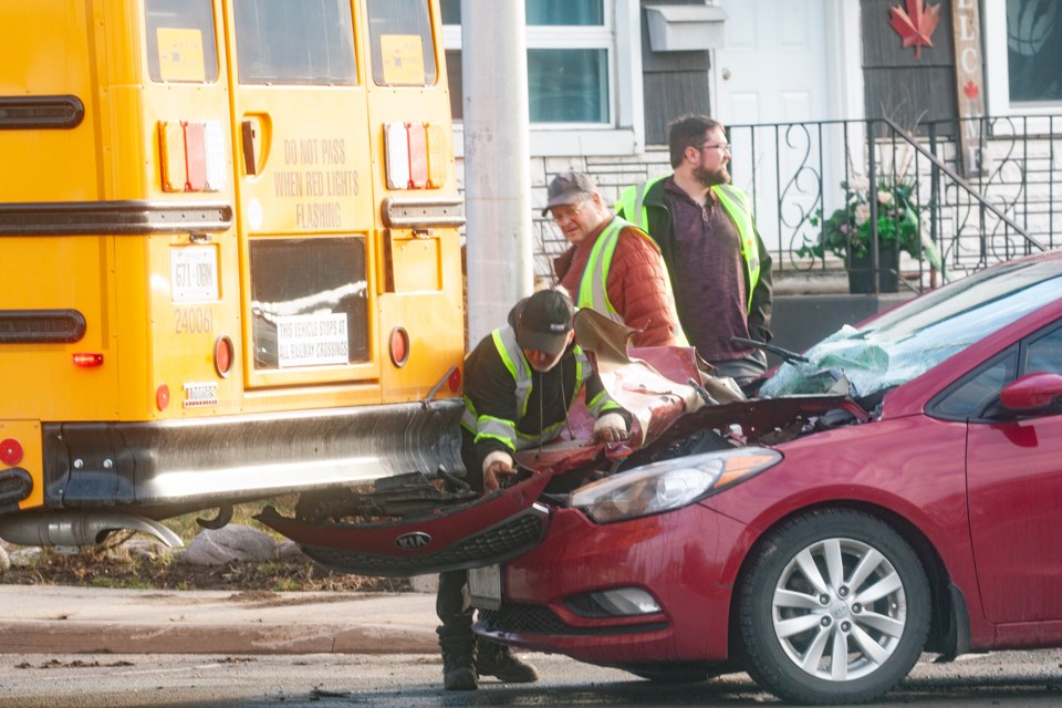 A tow truck operator examines the damage from a collision between a car and school bus that occurred Wednesday morning on Wellington Street East and Simpson Street.