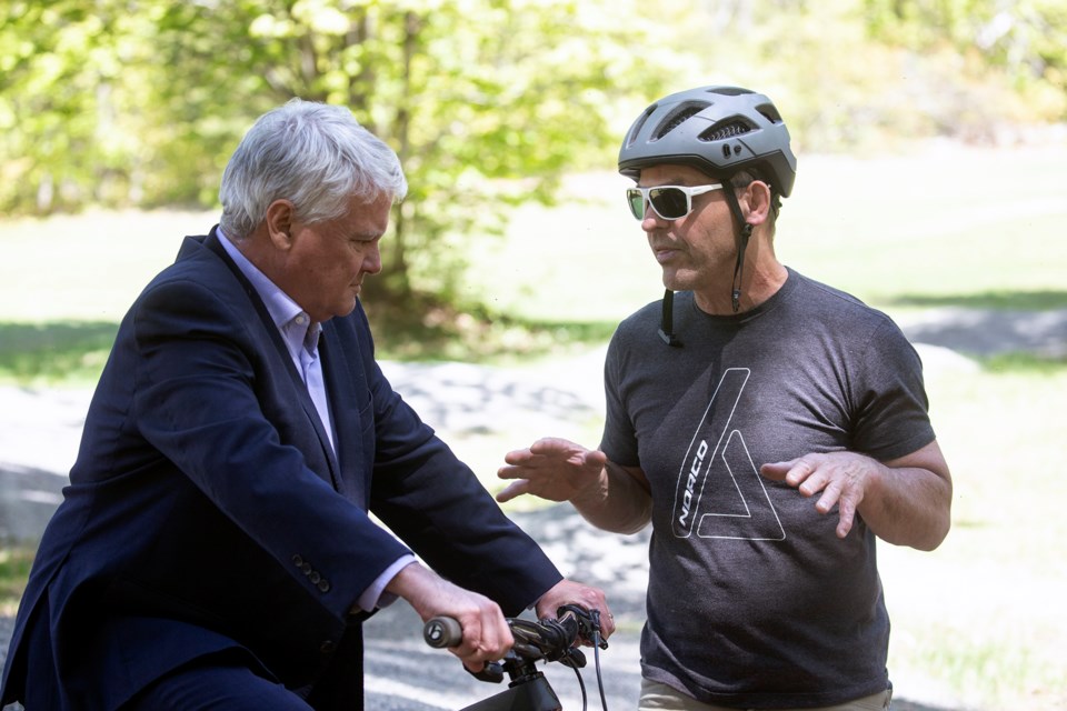 Sault MP Terry Sheehan sits on a bike while listening to local cycling advocate Andre Riopel immediately after an announcement on Friday of $1.2 million in multi-use trails that will link the city to Wishart Park and Hiawatha Highlands.