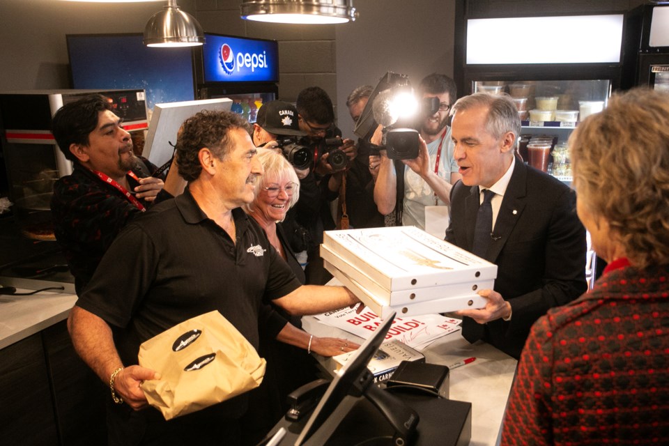Liberal Leader Mark Carney is handed a stack of Aurora's pizzas during a campaign stop in the Sault today.