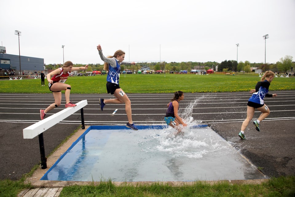 Runners splash through the water pit during the Girls open 1500m Steeplechase on Day 1 of NOSSA Track and Field at the Jo Forman Track in Sault Ste. Marie on Wednesday.