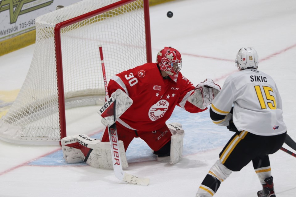 Soo Greyhounds goaltender Tucker Tynan watches the puck go past him as Sarnia Sting forward Marko Sikic looks on at the GFL Memorial Gardens on Feb. 12, 2022.