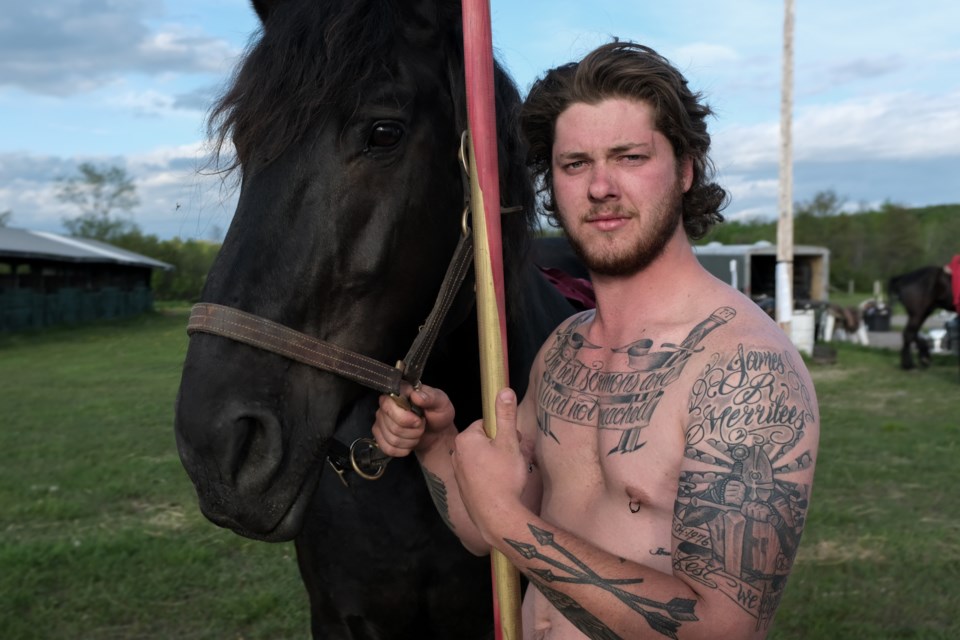 Knight Josh Tobey holds a lance and shows the tattoo he has in honour of of his now-deceased mentor James Merrilees at the Laird fairgrounds on Friday. Jeff Klassen/SooToday