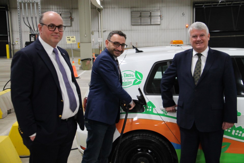 Omar Alghabra, federal Minister of Transport, charges an electric PUC vehicle accompanied by Rob Brewer, PUC Services president and CEO and Sault MP Terry Sheehan during Alghabra’s tour of PUC Services, April 5, 2023.
