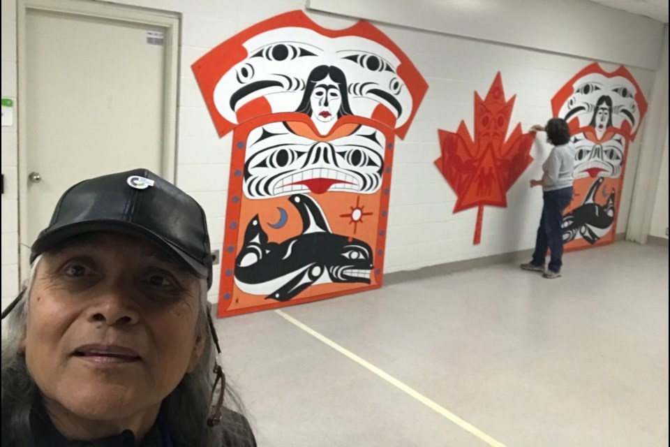 Xwalacktun with his installation at Brennan Park Recreation Centre.  
Glenne Campbell is in the background. 