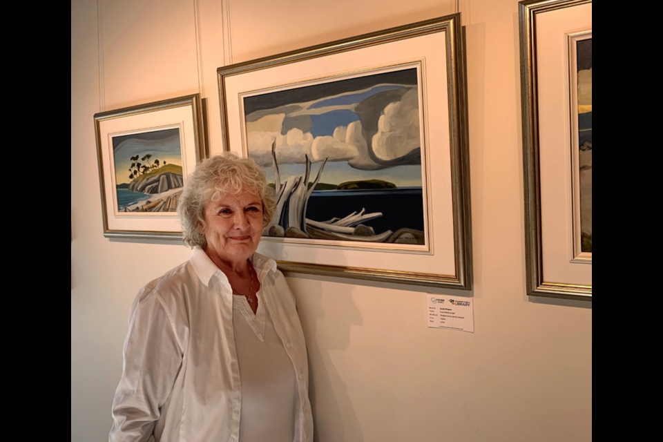 Linda Wagner beside "From Rebecca Spit," her favourite painting in the current "Coastal Waters," show. 