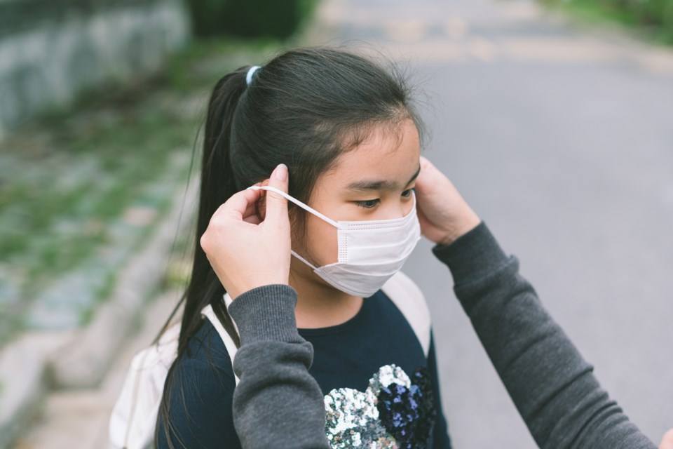 Mother puts a mask on daughter to prepare go to school.