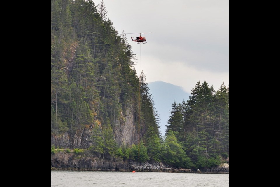 Crews bucket the small wildfire at Porteau Cove last week. 
