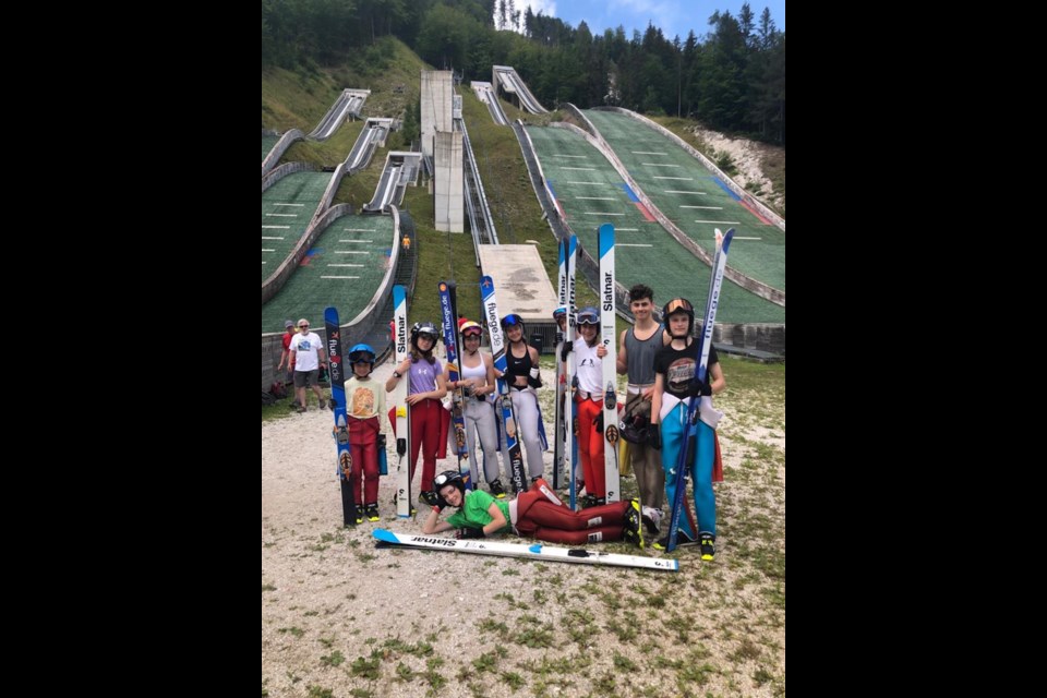 Left to right:  Ethan Bell, Ella Boa, Sofia Aragon, all of Squamish; Olivia Heron and Tarik VanWieren (partially hidden), both of Calgary; Mitchell Penning, of Toronto; Tyler Sopp and Dyllon Crawford, both of Whistler.
Foreground:  Ben Leachman, of Calgary; in the background far left: Sea to Sky Nordics members, Rick Smith in red, and Jim Woolsey in white, coming down from the judges' tower following the competition.