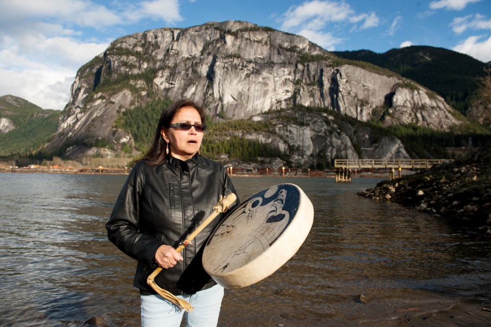 Squamish Nation knowledge keeper Tsawaysia Spukwus drums in front of the Stawamus Chief,