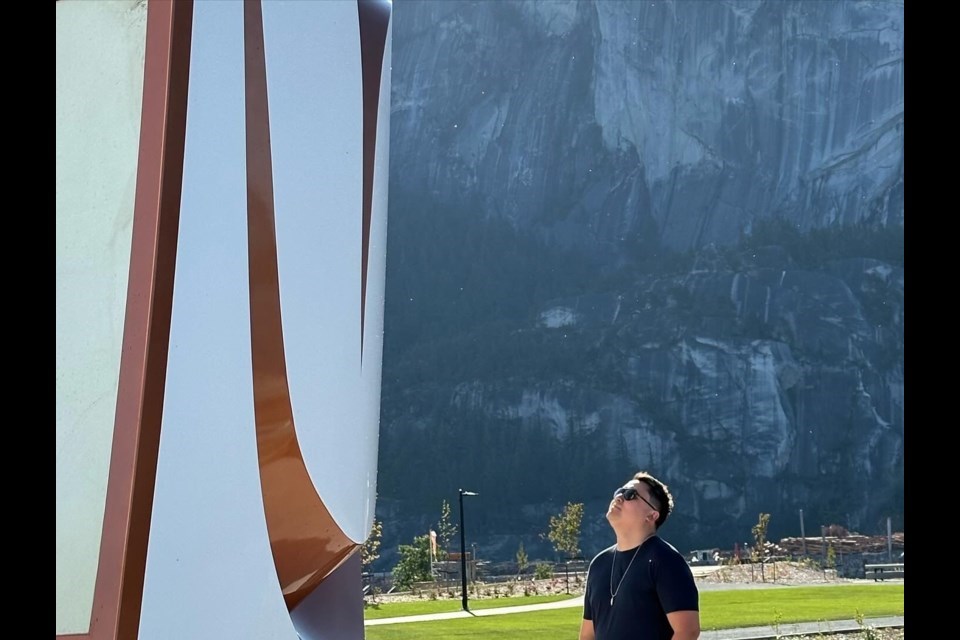 James Harry, a Sḵwx̱wú7mesh 
artist whose work is featured at the 鶹Arts Festival. Here is stands with Welcome Gate on the oceanfront in Squamish.