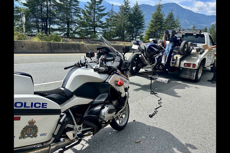 A Suzuki motorcycle getting towed in front of a BC Highway Patrol BMW.