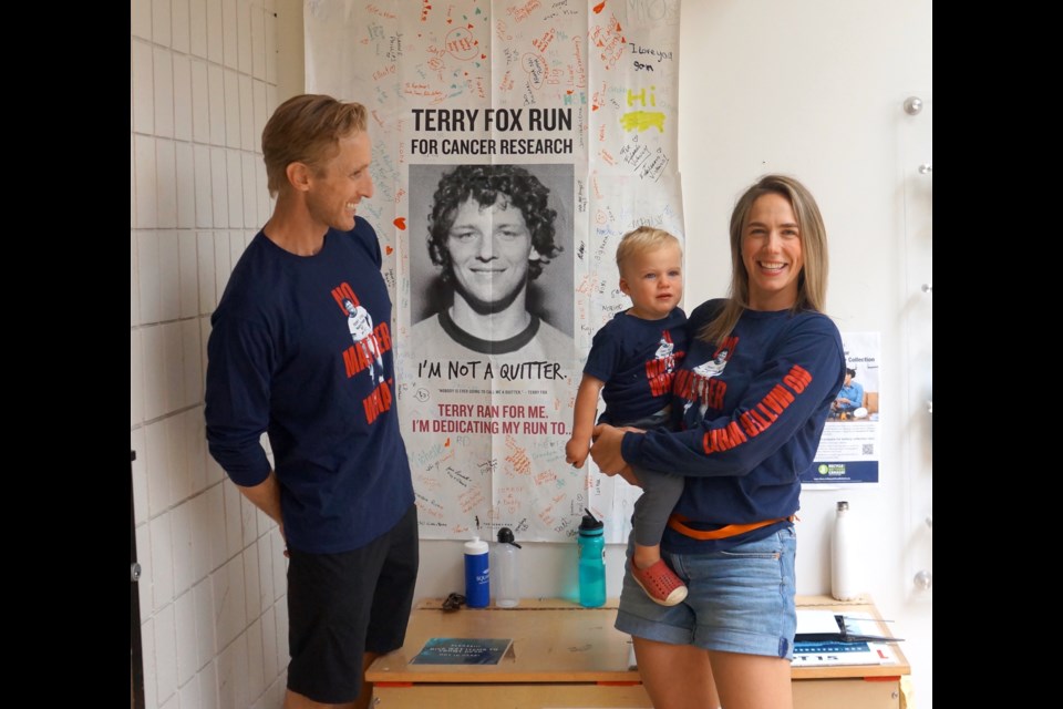 Organizers Jon Milnes and Magee Walker, with her son, by the Terry Fox poster at Brennan Park Recreation Centre on Thursday.                             