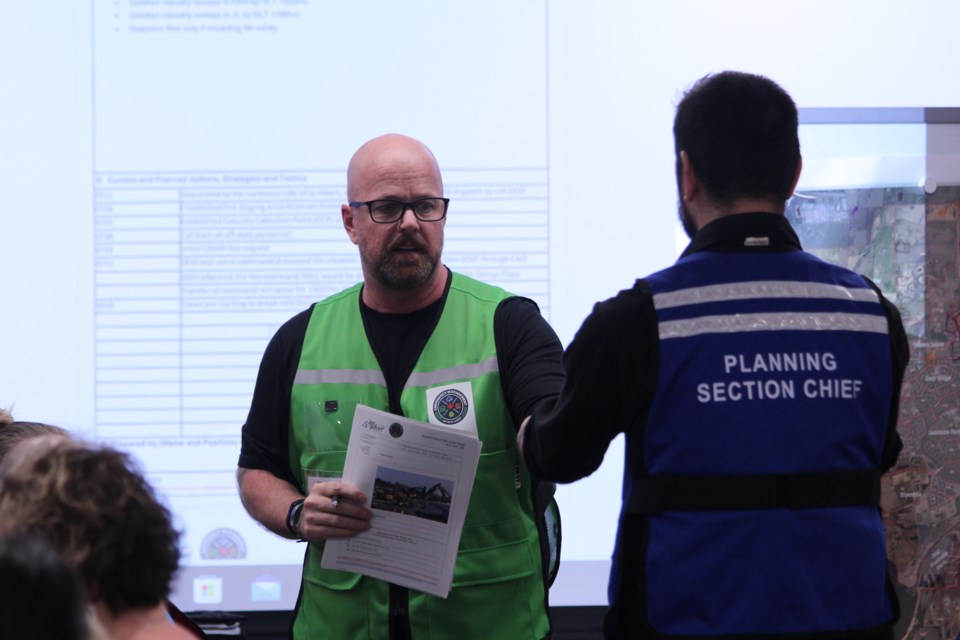 The City of St. Albert's emergency management manager, Mark Pickford (left), receives a report from a city staff member during the April 25 tabletop exercise at Fire Hall #1. JACK FARRELL/St. Albert Gazette