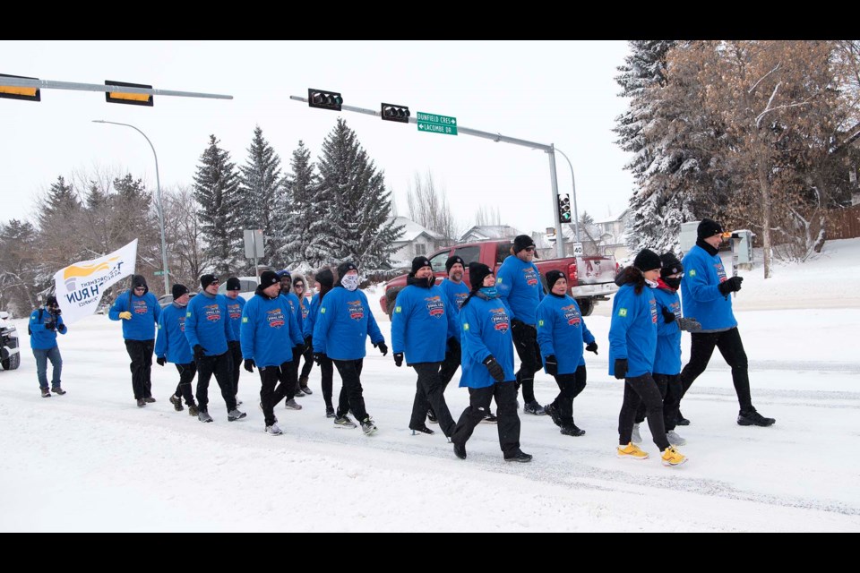 WINTER STROLL — Torchbearers for the 2024 Special Olympics Canada Winter Games carry the Olympic torch down Giroux Road en route to Bellerose Composite on Feb. 26. The torch was in St. Albert to highlight Bellerose’s commitment to Special Olympics. KEVIN MA/St. Albert Gazette
