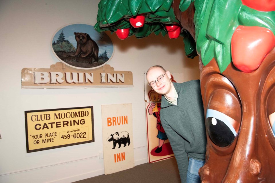 CLASSIC LANDMARKS — Musée Héritage Museum curator Martin Bierens peers around the St. Albert Public Library apple tree statue. The statue was one of many signs and landmarks featured in the Signs of the Times exhibit, which opened March 4, 2025. 