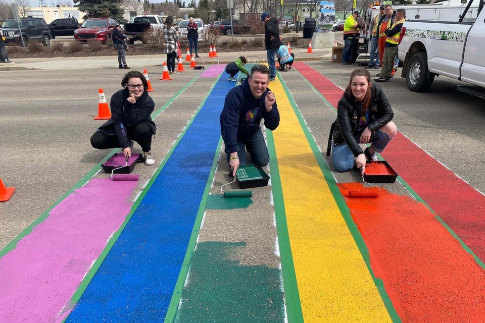 RAINBOW ROAD — Outloud St. Albert members Bekah Marcellus (left), Terry Soetaert, and Kelsey Robbins repaint a rainbow-themed crosswalk in front of St. Albert Place in May 2022. OUTLOUD ST. ALBERT/Photo