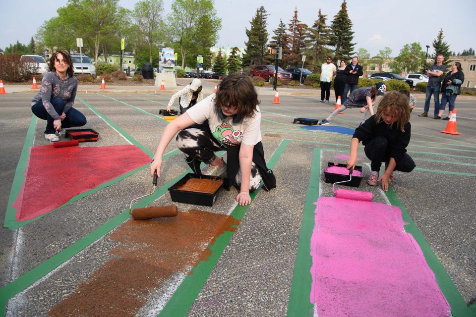 NEW PAINT JOB — Volunteers paint a rainbow crosswalk in front of St. Albert Place May 25 in preparation for Pride Month (June). This year's crosswalk is based on the Progress Pride flag, which includes additional coloured chevrons to represent trans people and marginalized communities of colour. KEVIN MA/St. Albert Gazette