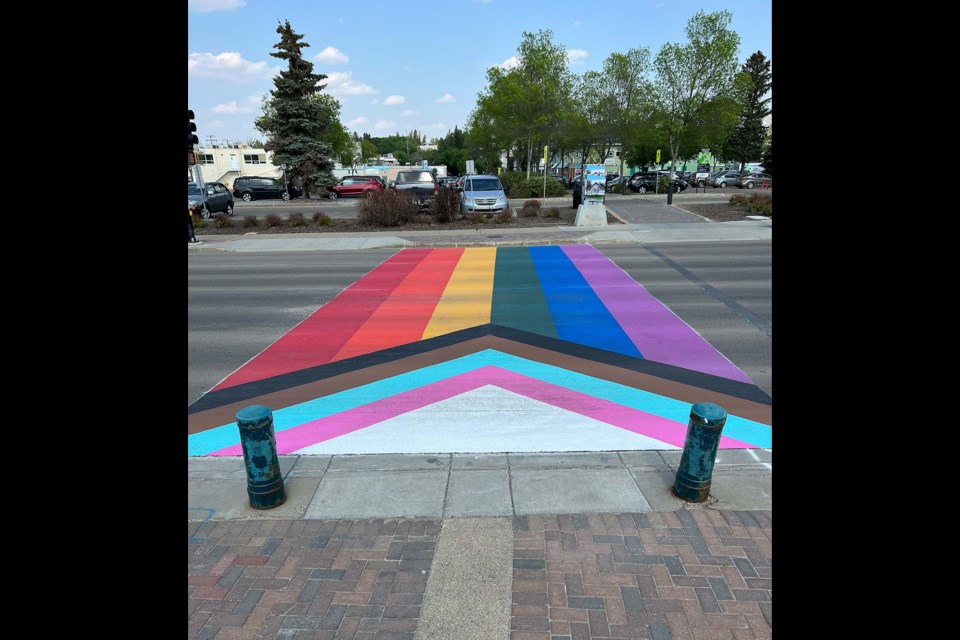 The finished Progress Pride crosswalk in front of St. Albert Place as of May 26, 2023. The vertical stripes represent the LGBTQ community as a whole, while the chevrons represent trans people and marginalized communities of colour. OUTLOUD ST. ALBERT/Photo