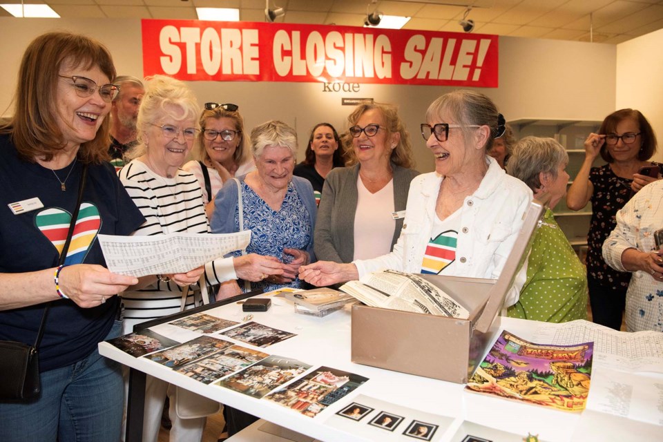 TREASURES REVEALED — Guests marvel at items found in a time capsule installed at the St. Albert Hudson's Bay outlet in 1995 and opened on June 1, 2025. Shown here are photos, work documents, and a comic book from the capsule. Longtime store employee Jeanie Epp (in white) had the honour of opening the capsule. KEVIN MA/St. Albert Gazette